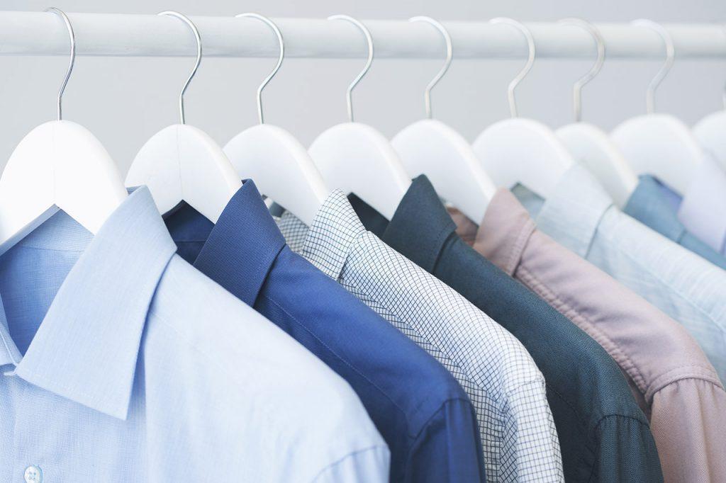 Assorted blue shirts hanging on wooden hangers